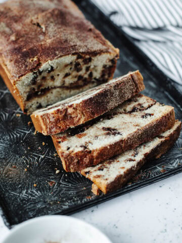 sliced Snickerdoodle Bread with mini chocolate chips throughout on a black cutting board.