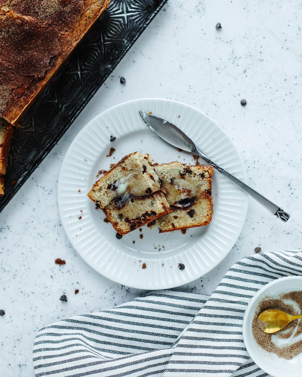 Cinnamon swirl bread sliced and ready to enjoy on a white plate with butter.