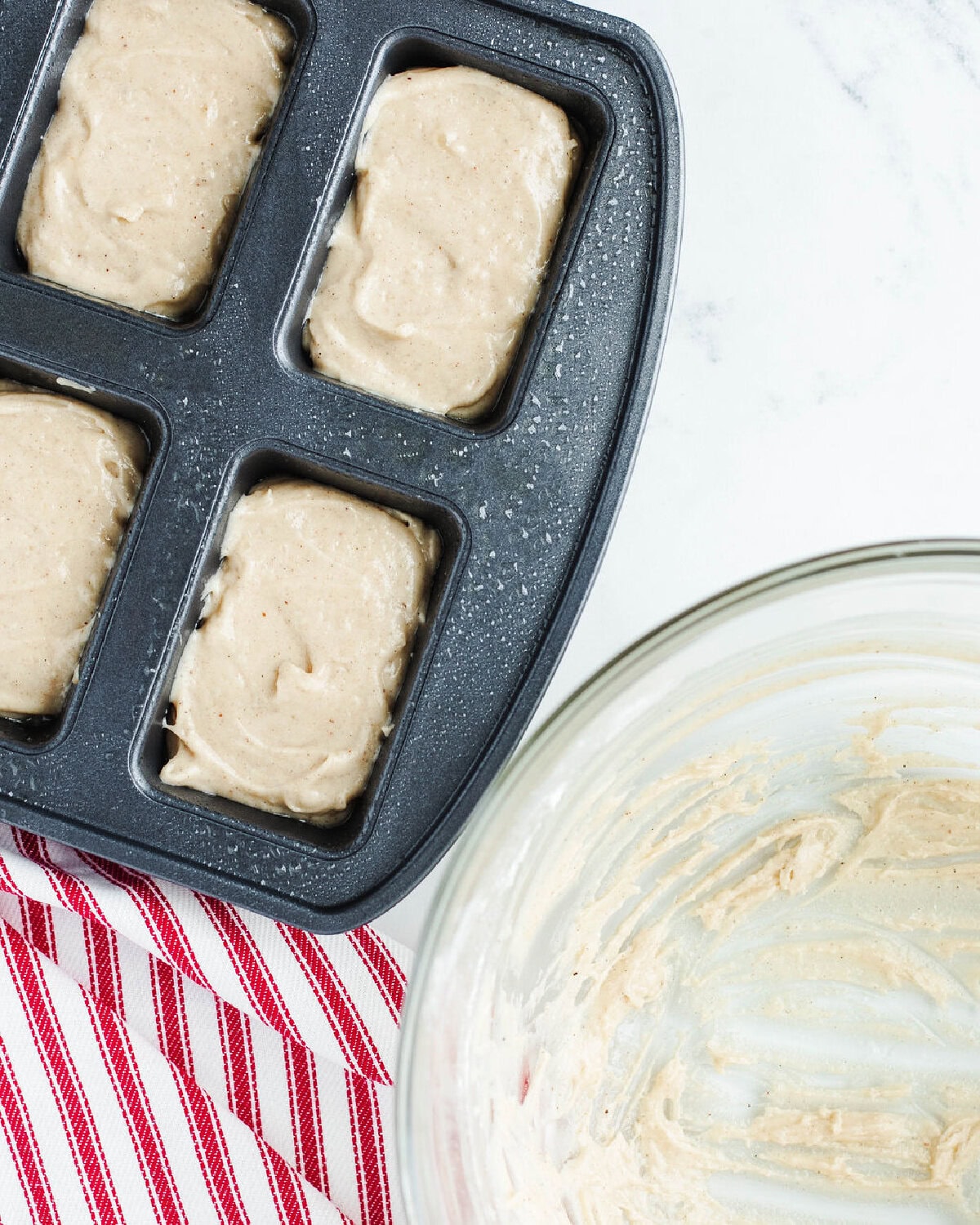 quick bread batter poured into a greased mini loaf pan tray.