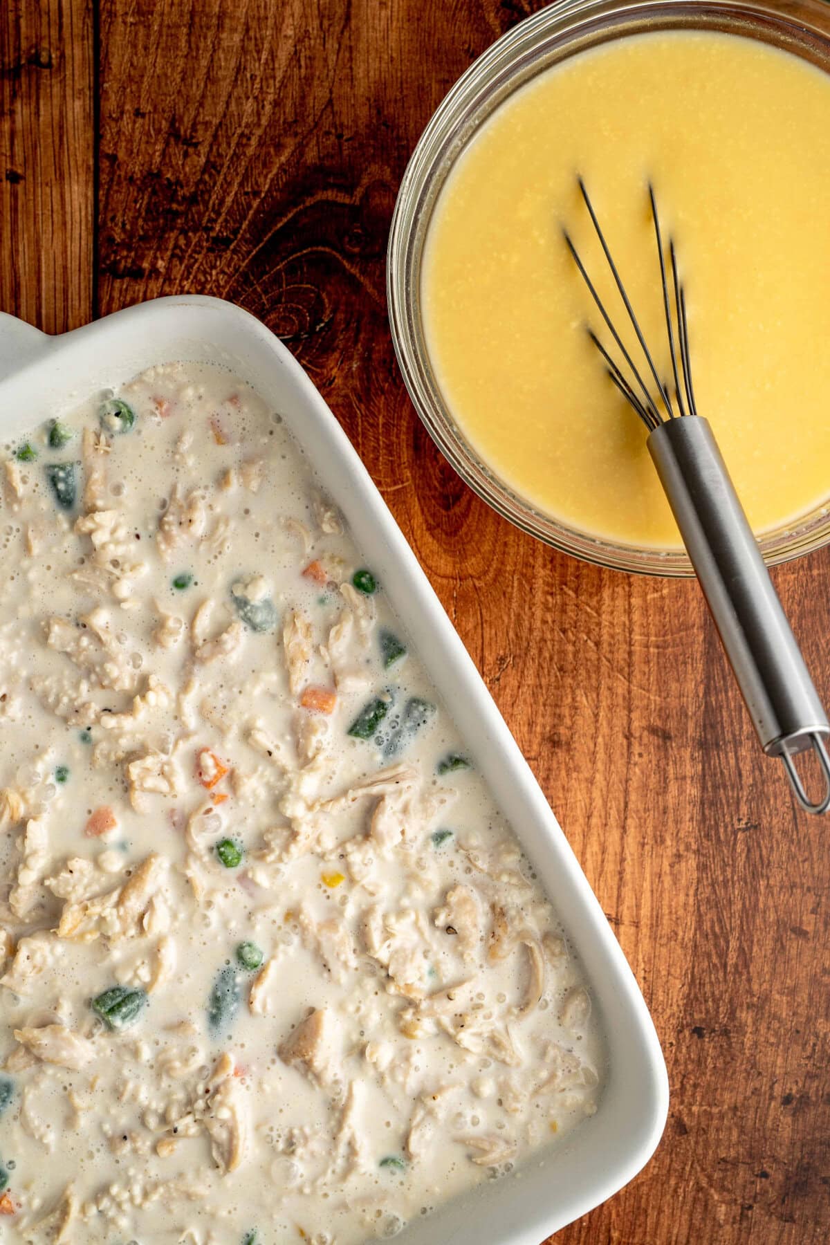 biscuit mixture poured on top of chicken and veggies in a dish.