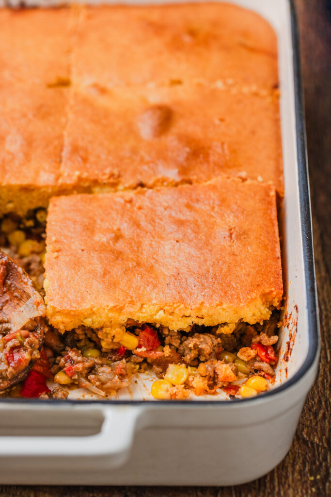 an up-close look at layered beef bake with cornbread, beef, corn, and tomatoes combined.