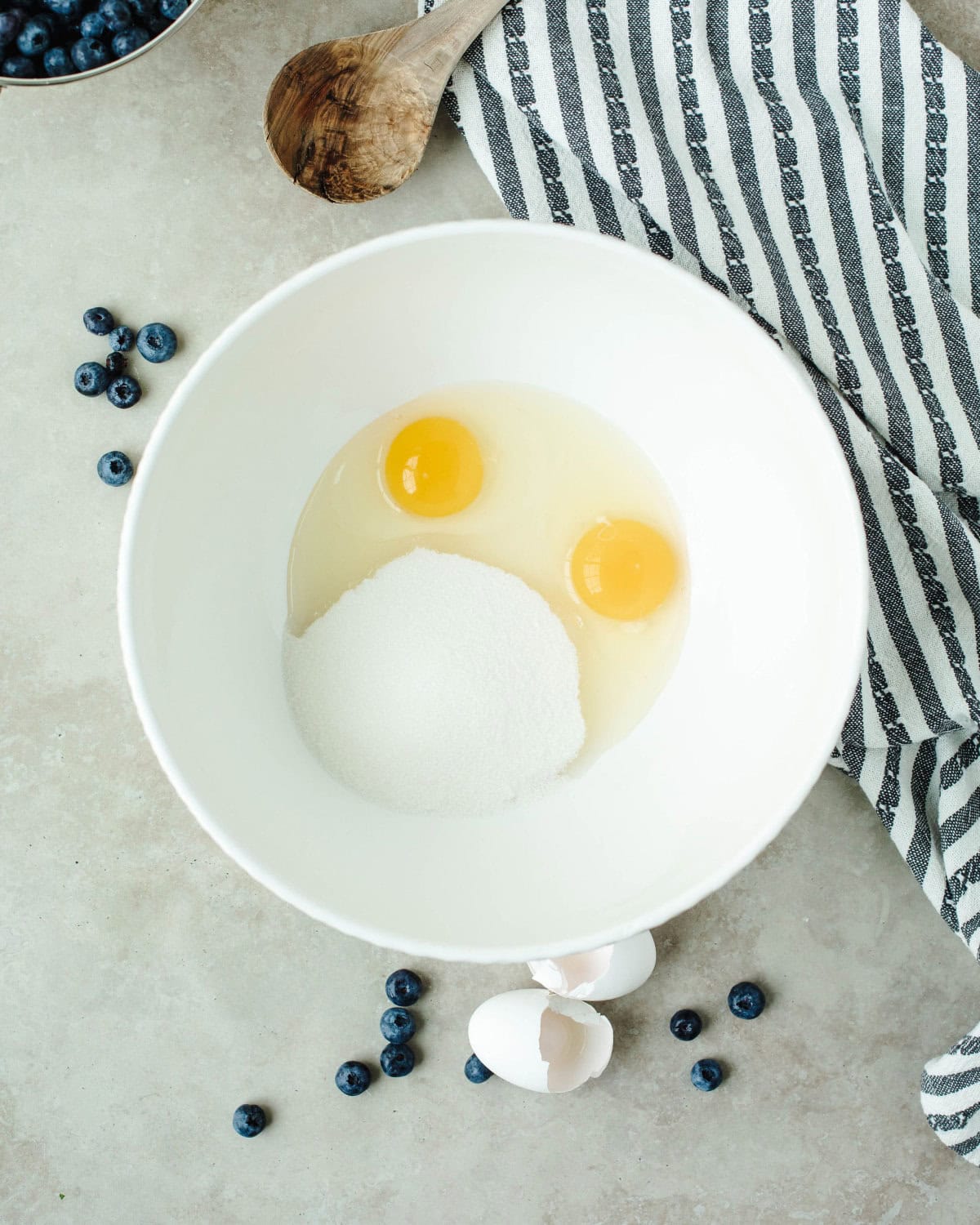 eggs and sugar whisked together in a white mixing bowl.