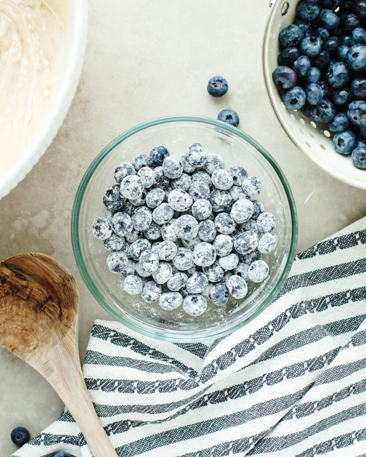 a glass bowl with blueberries tossed in flour to prevent sinking.