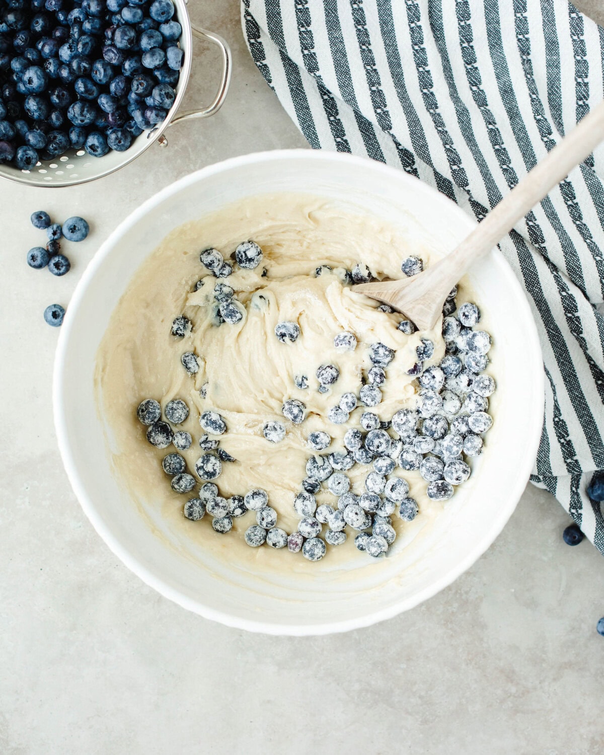 blueberries folded into batter in a mixing bowl.