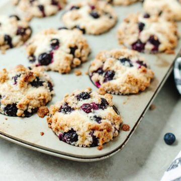 baked blueberry muffins with cinnamon topping baked in a muffin pan.