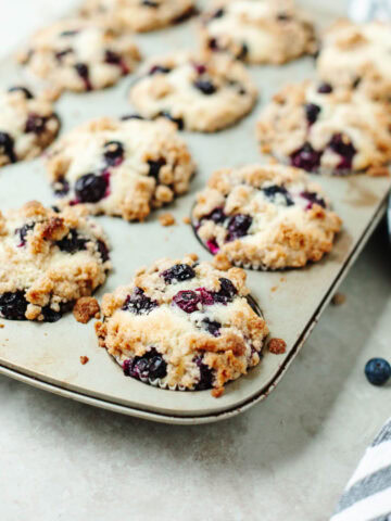 baked blueberry muffins with cinnamon topping baked in a muffin pan.