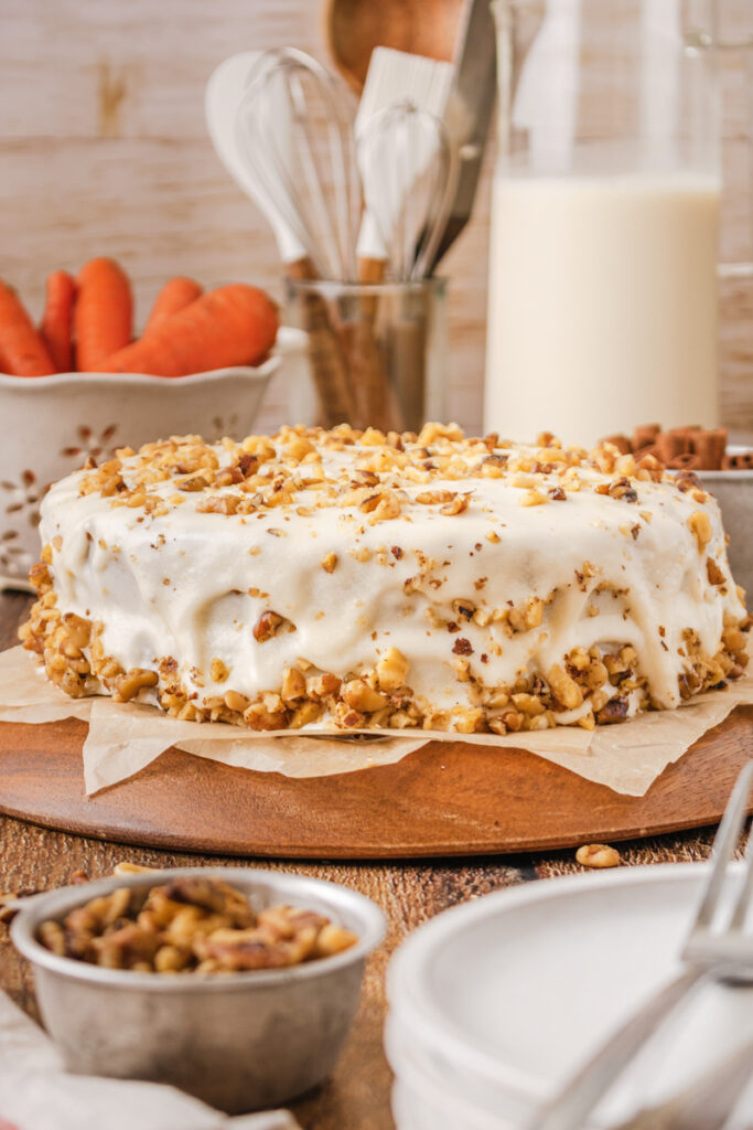 a cream cheese frosted carrot cake on a cake stand.