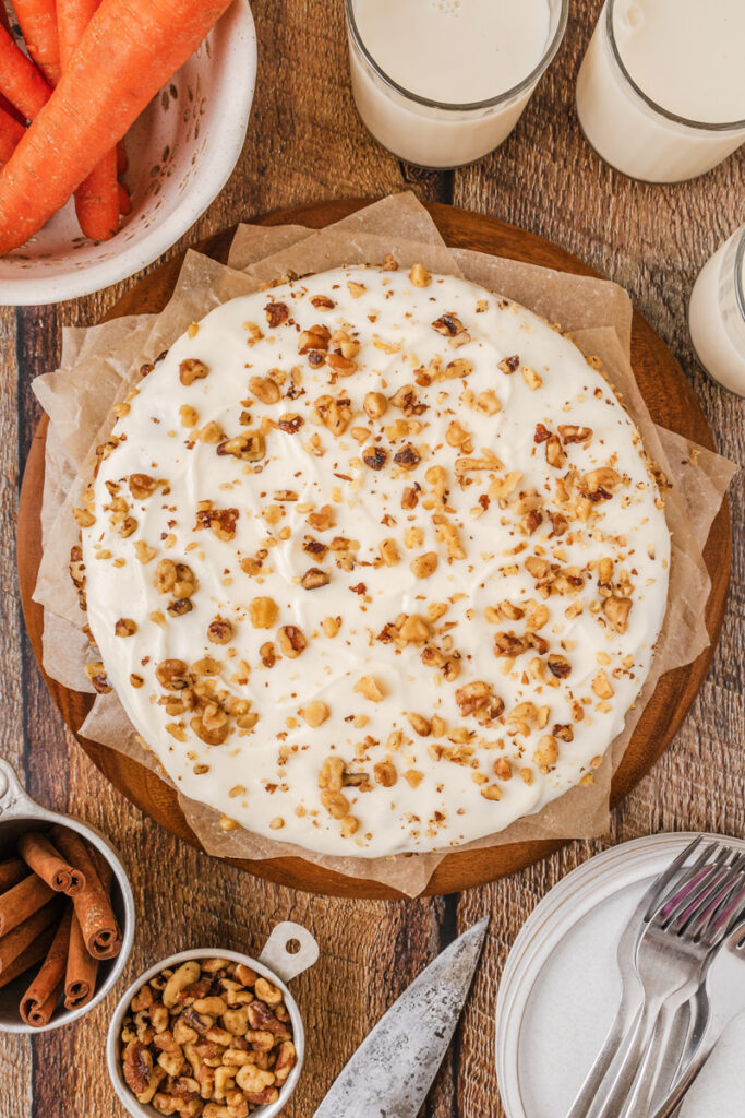 the top view of a carrot cake with cream cheese frosting and walnuts sprinkled on top.