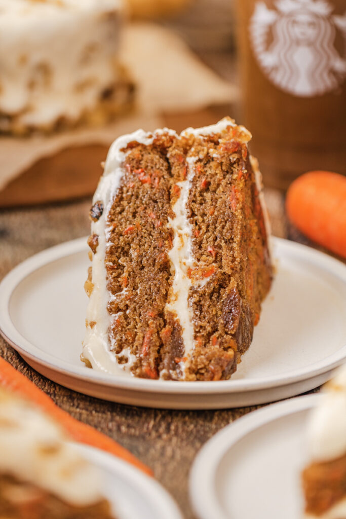 the side view of spiced carrot cake with cream cheese frosting on top and in the middle.