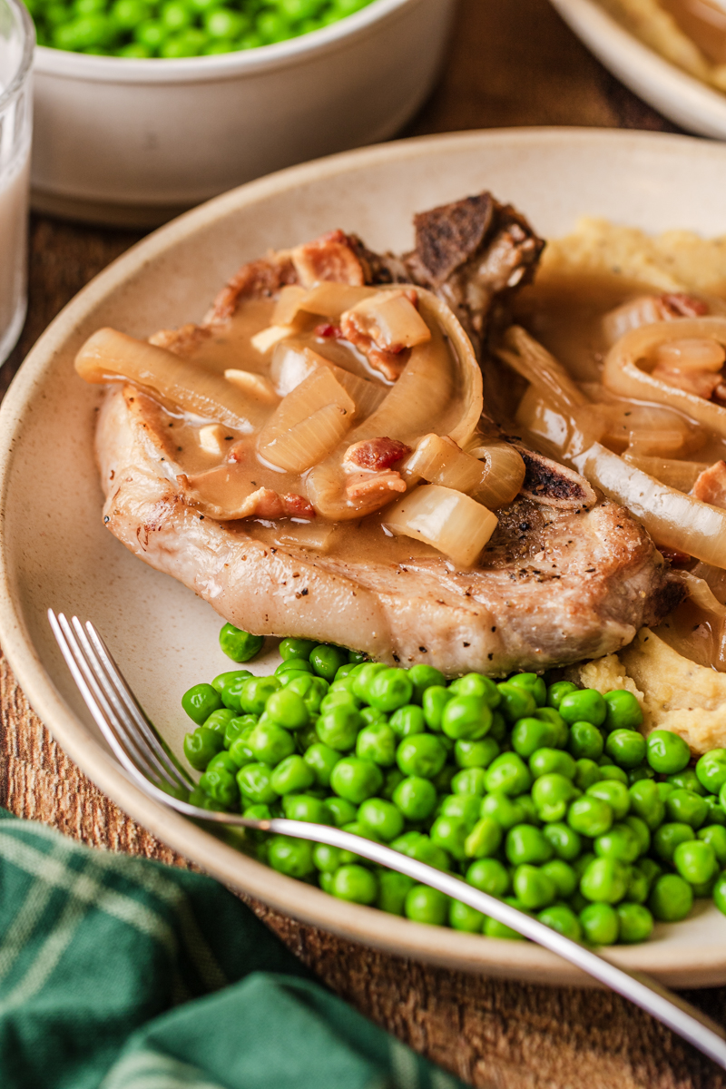 smothered pork chops on a plate with peas