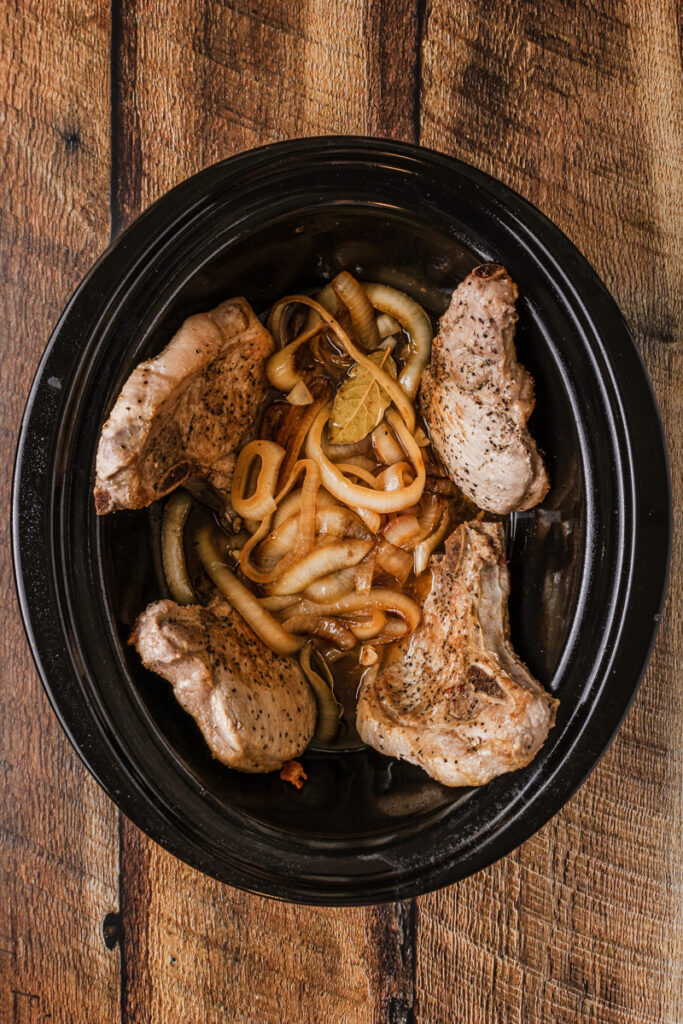 pork chops, onions, garlic, and seasoning in a slow cooker.