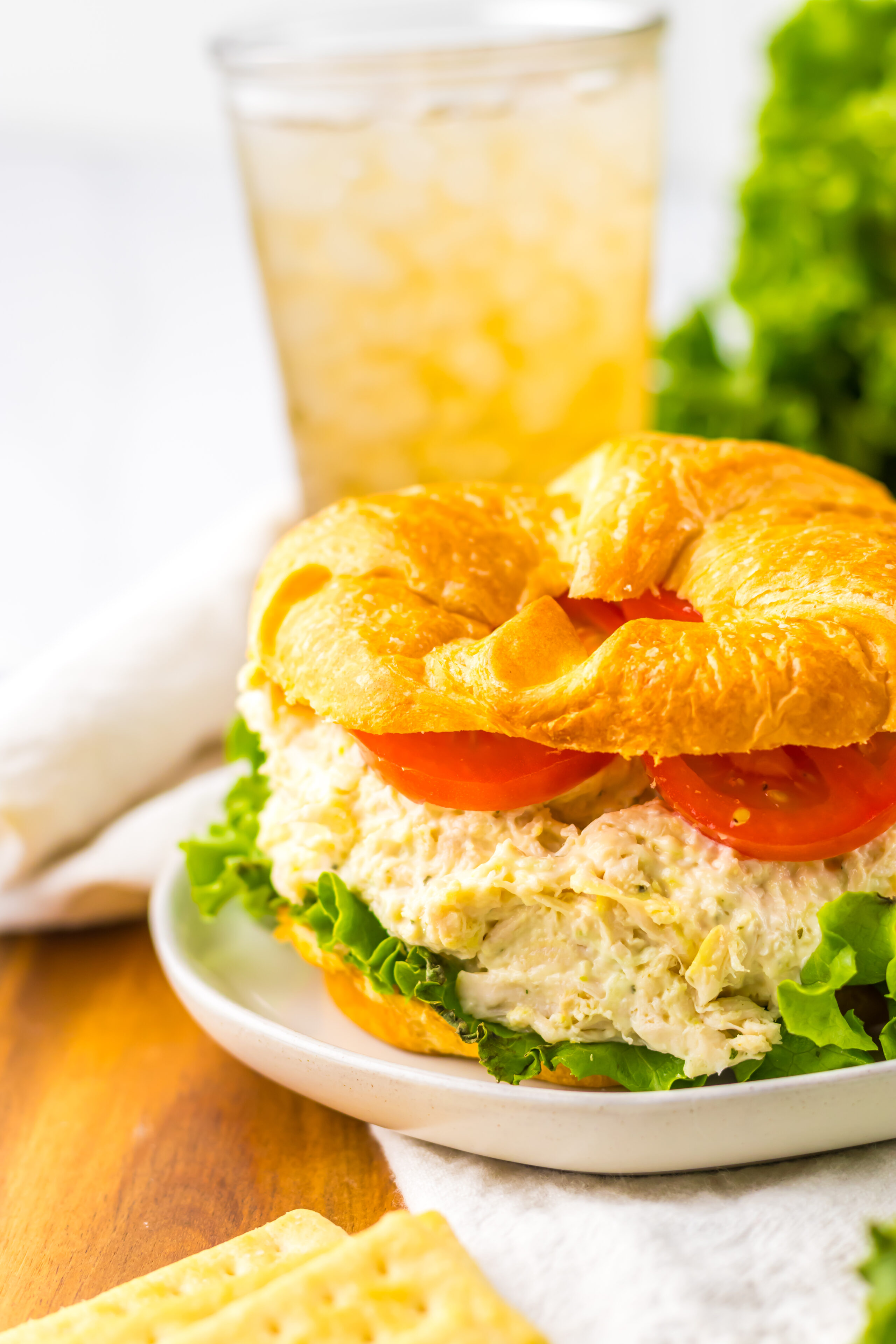 chicken salad served on a croissant with lettuce and tomato.