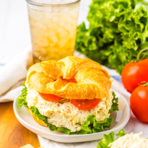 a sandwich made with shredded chicken, mayonnaise, celery, and topped with lettuce and tomato.