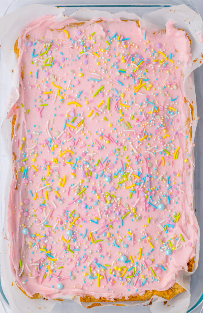 pink frosted sugar cookie bars topped with sprinkles.