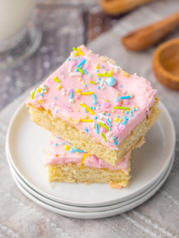 frosted sugar cookie bars topped with sprinkles on a plate.
