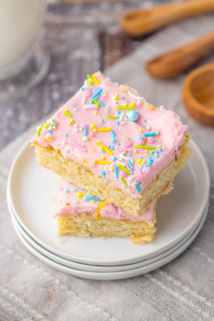 frosted sugar cookie bars topped with sprinkles on a plate.