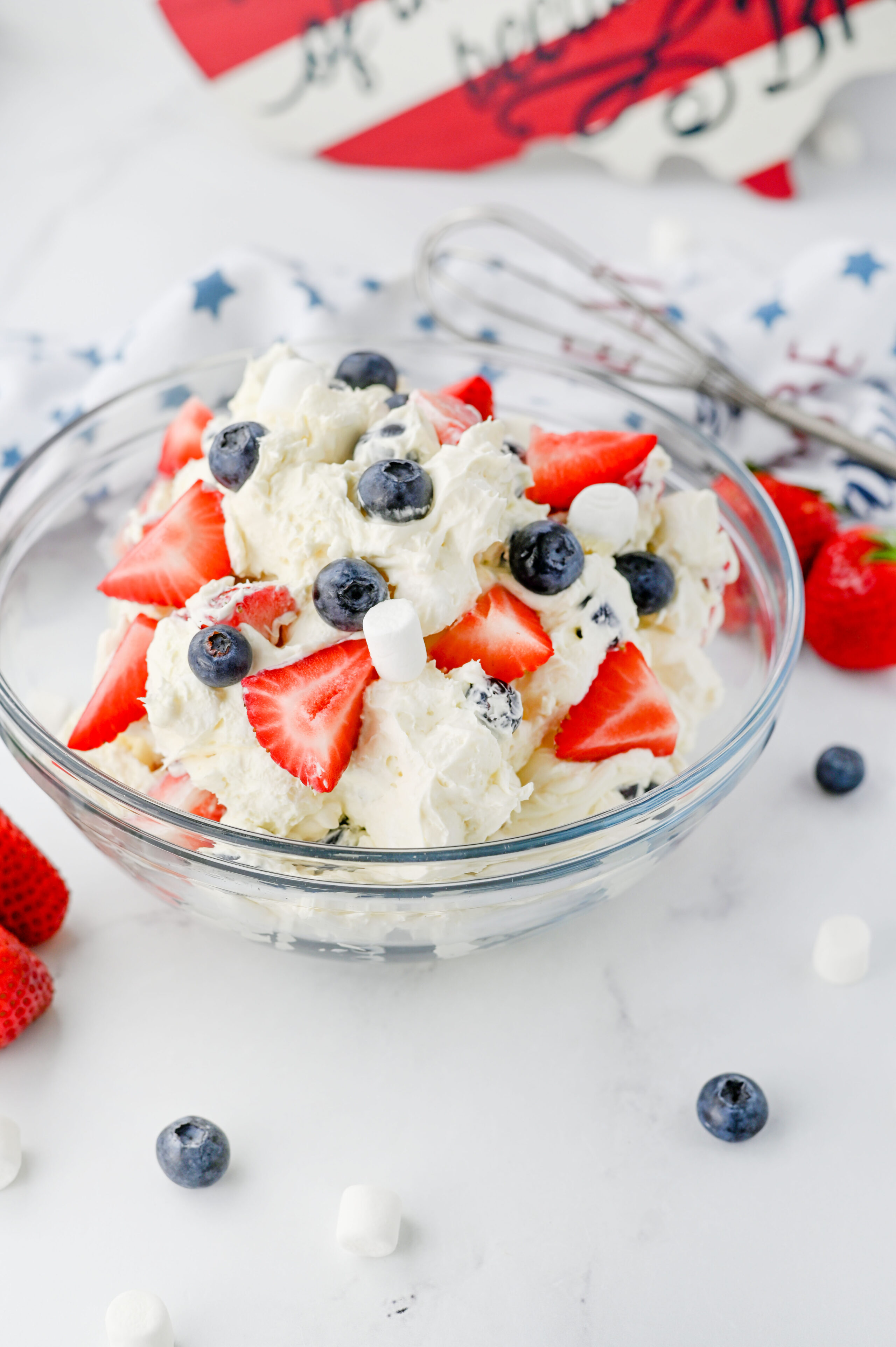 creamy cheesecake salad made with strawberries and blueberries in a glass bowl.