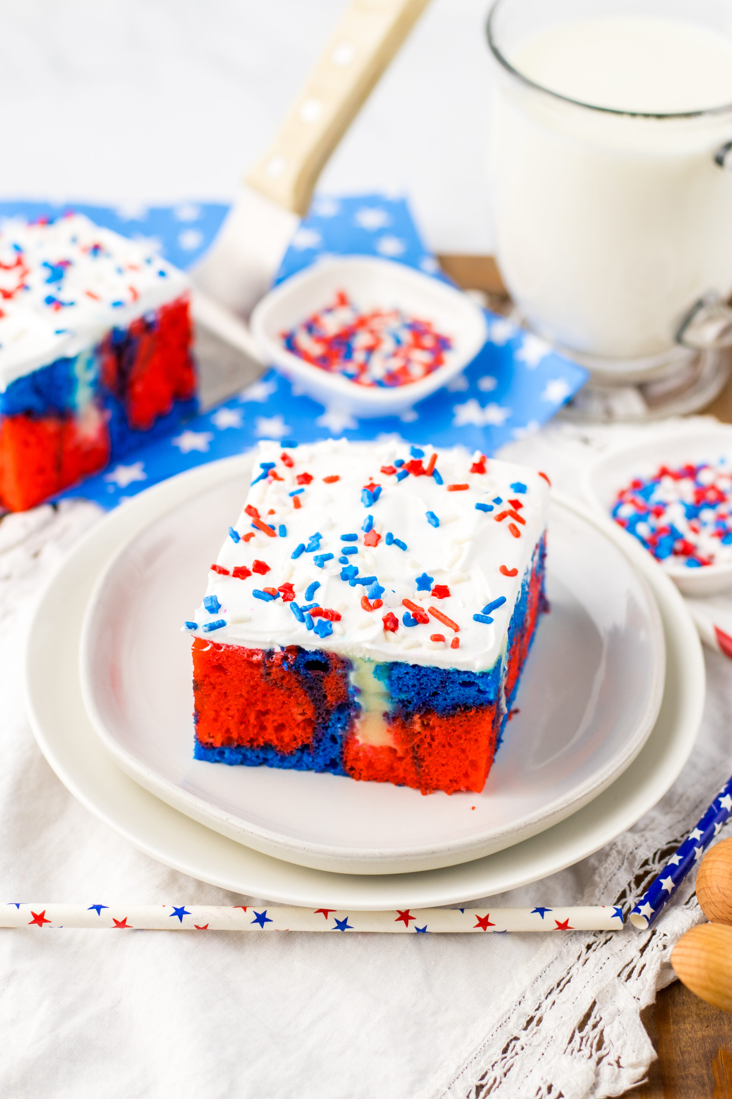 a piece of red, white, and blue poke cake served on a white dessert plate.