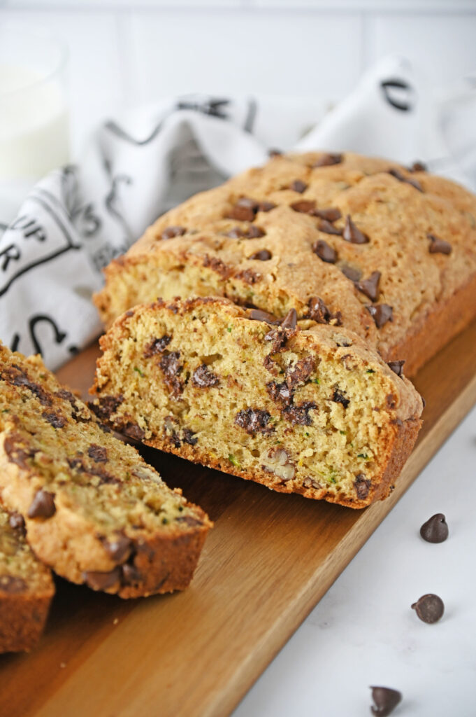 chocolate chips throughout a loaf of fresh zucchini bread on a cutting board.