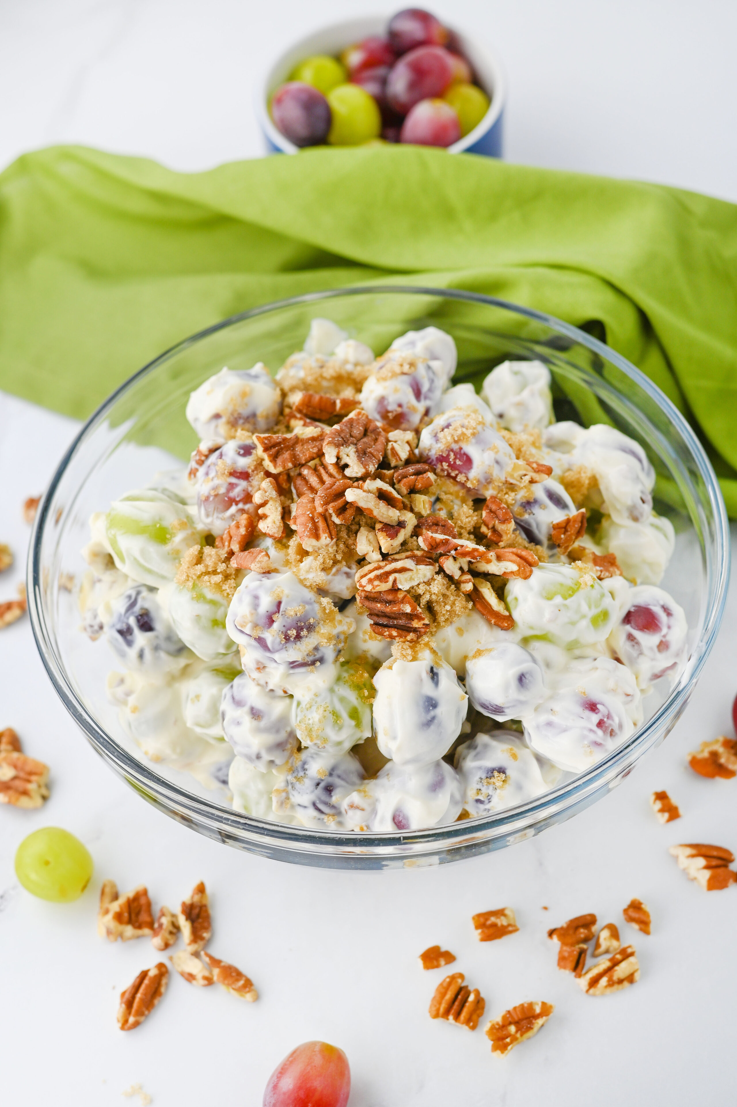 grape salad topped with crunchy nuts and brown sugar in a glass bowl.
