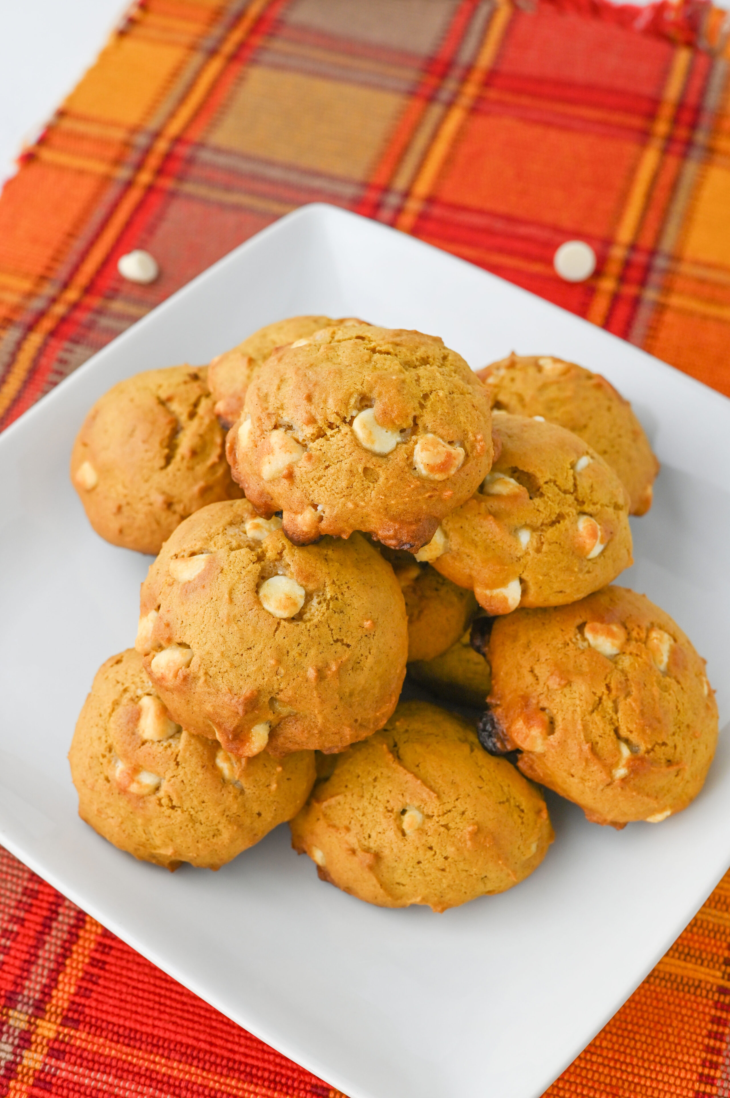 pumpkin cookies with white chocolate chips on a white plate.