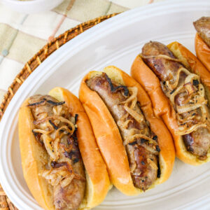 sausages cooked and placed in hot dog buns served with sauerkraut on top.
