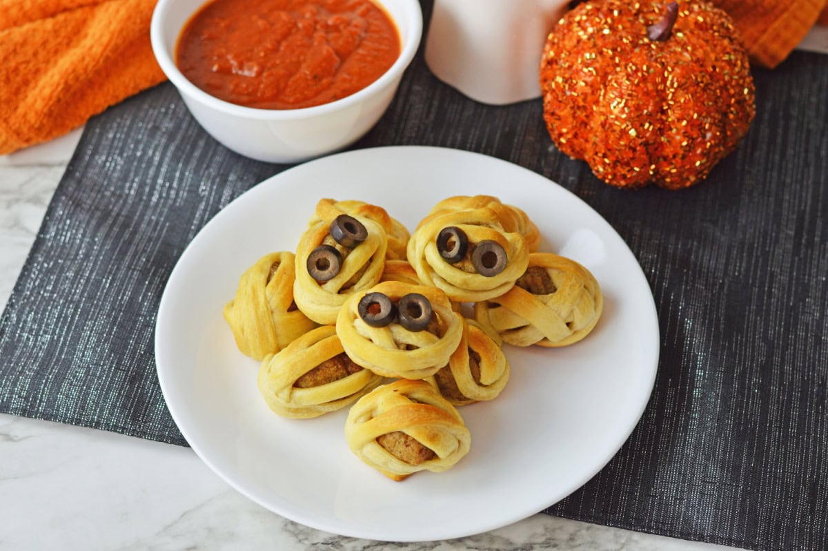 a baked appetizer on a white plate with marinara sauce.