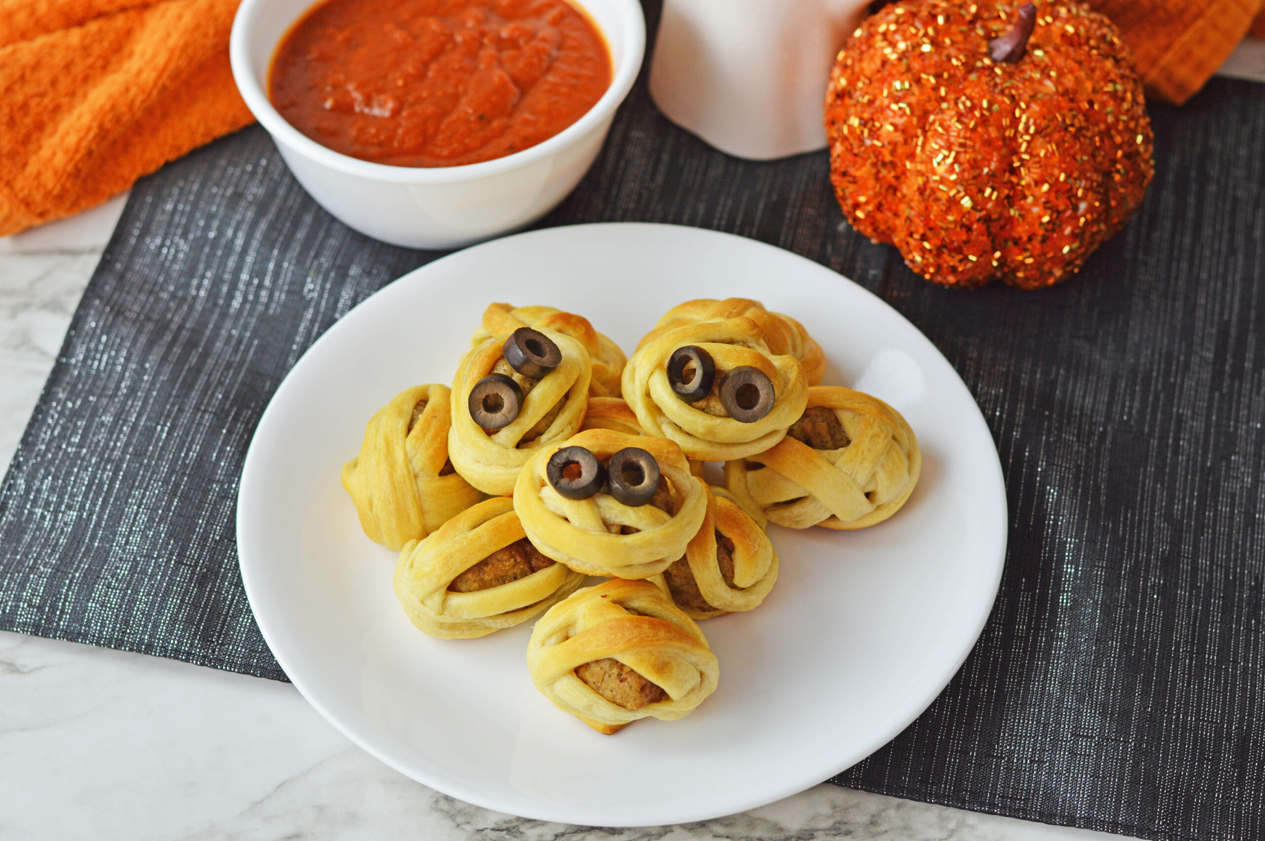 a white plate with mummy meatballs on it.