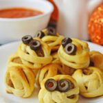 spooky Halloween meatballs served on a white plate with marinara sauce.