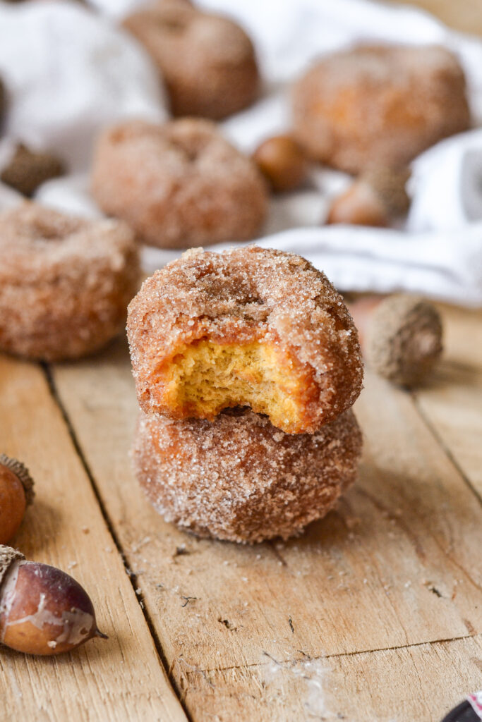 pumpkin spice donuts stacked on a wood board.