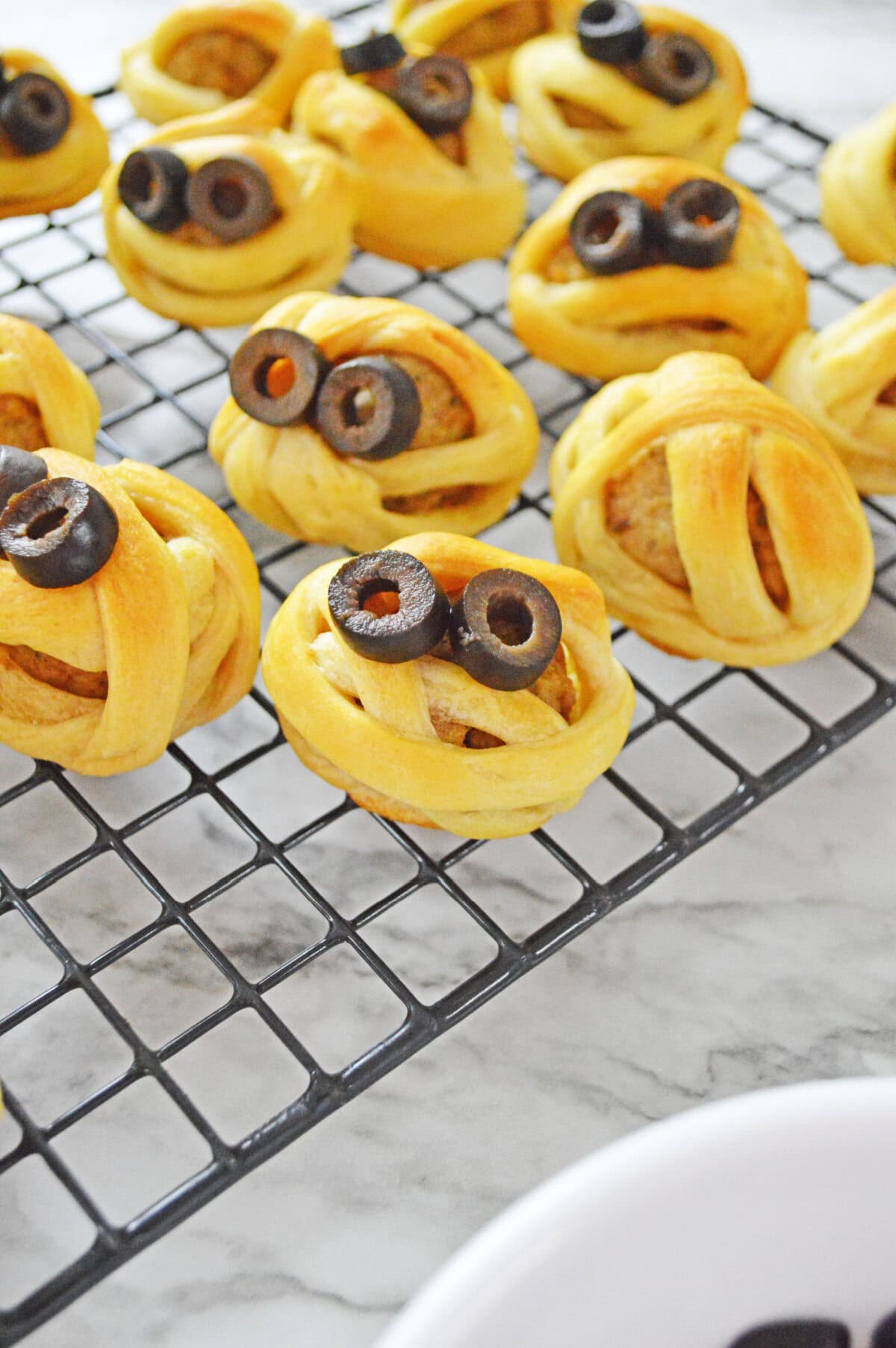 black olive slices used for eyes on baked meatballs wrapped in crescent roll dough.