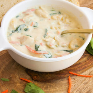 a bowl of soup in a white bowl with bread.