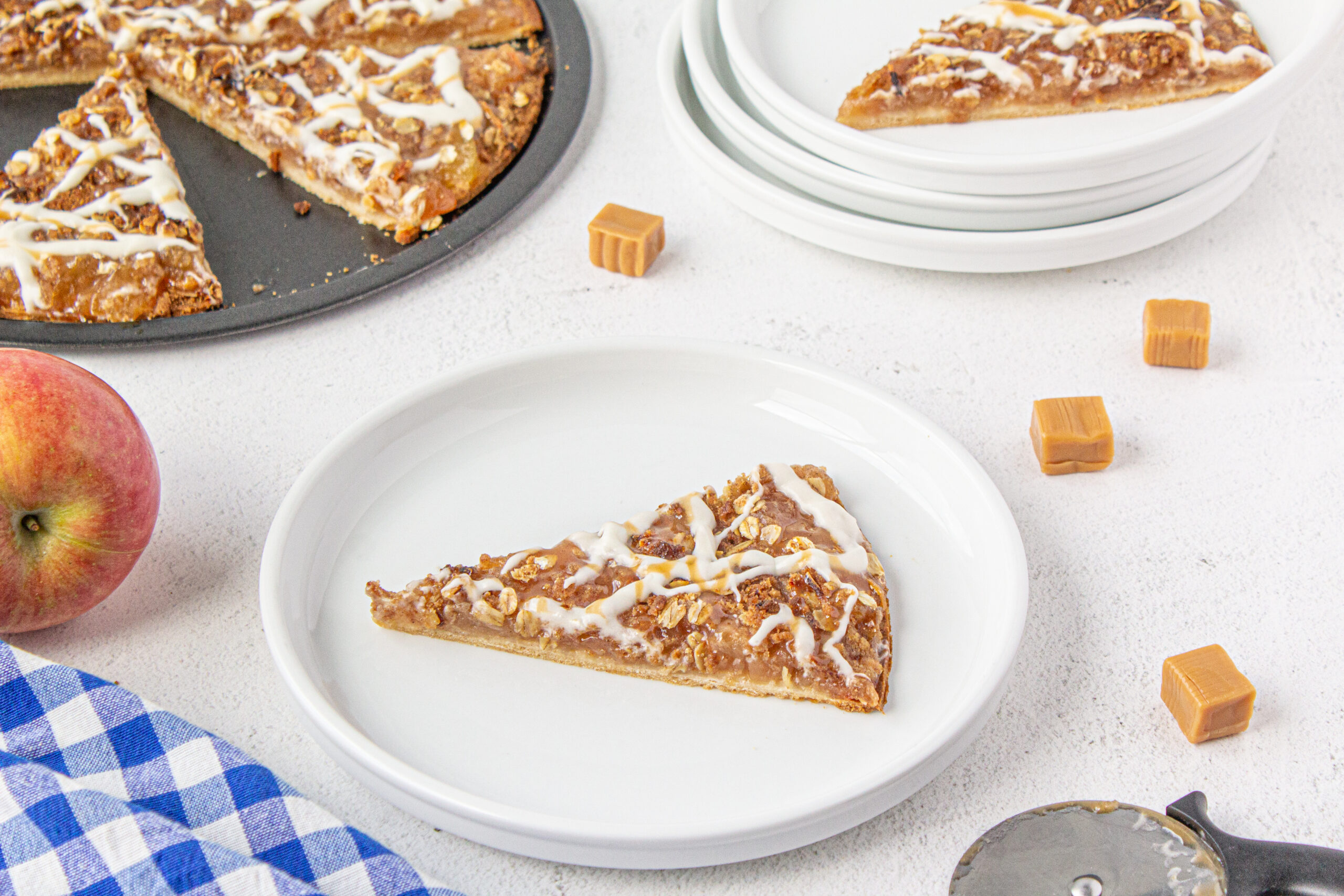 a white dessert plate with apple pizza on it ready to enjoy.