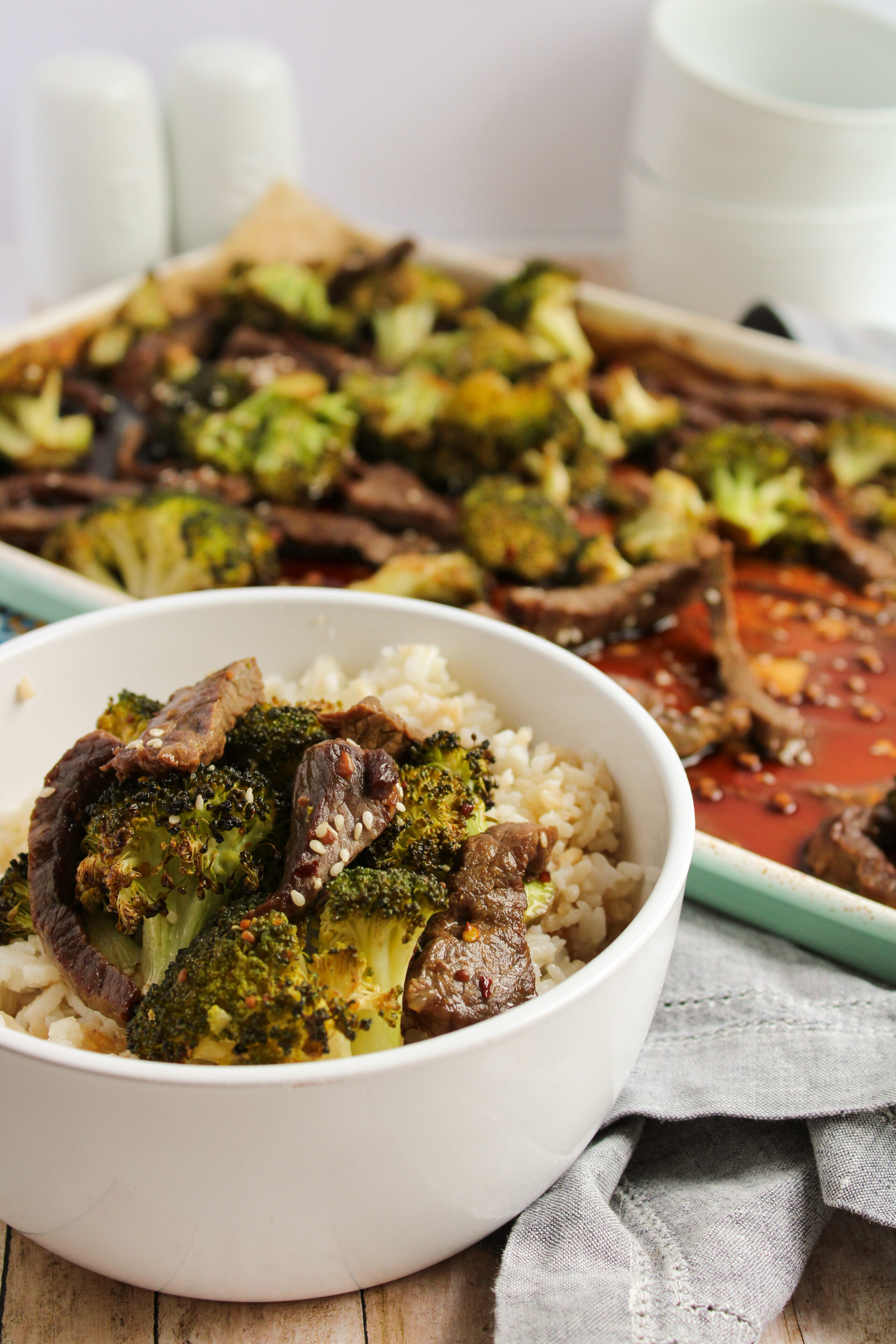 sheet pan beef and broccoli served in a white bowl with rice.