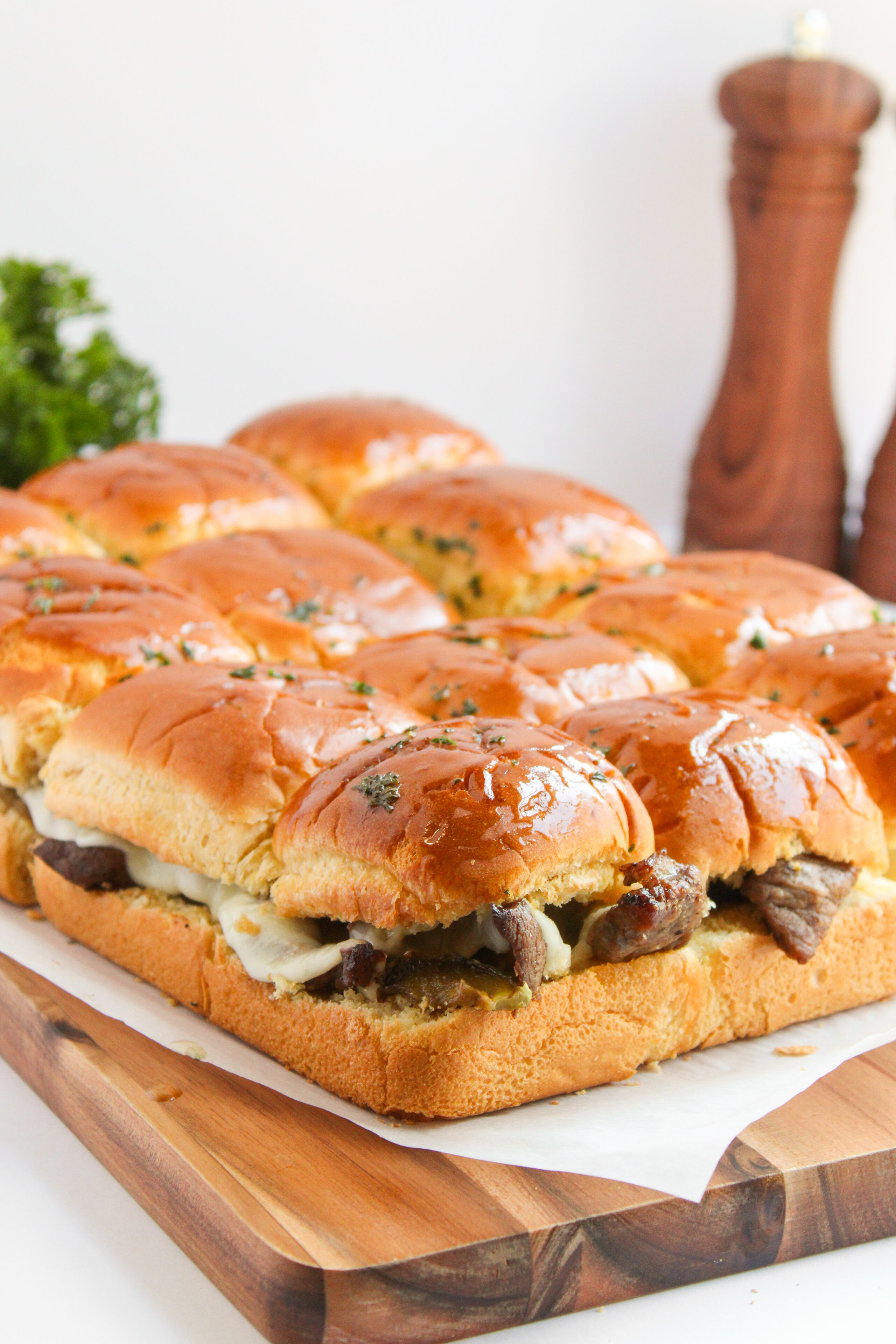 Philly cheesesteak sliders on a wood cutting board.