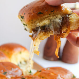 Philly Cheesesteak sliders being pulled to show the melted cheese.