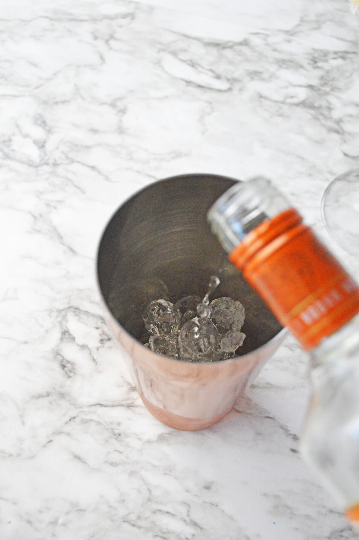 ice and caramel vodka added to a cocktail shaker.