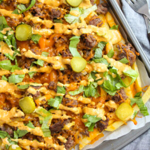 melted cheese over potato cuts with toppings and sauce.