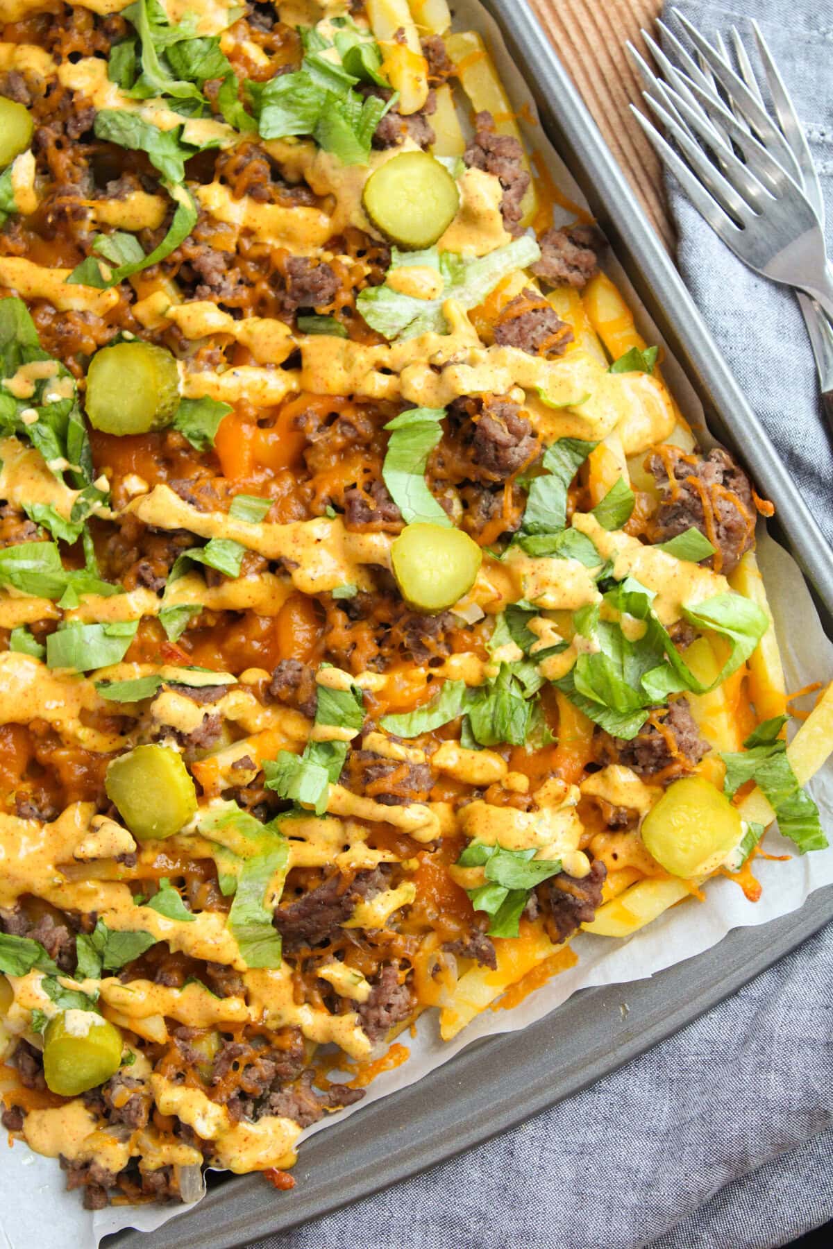 melted cheese over potato cuts with toppings and sauce.