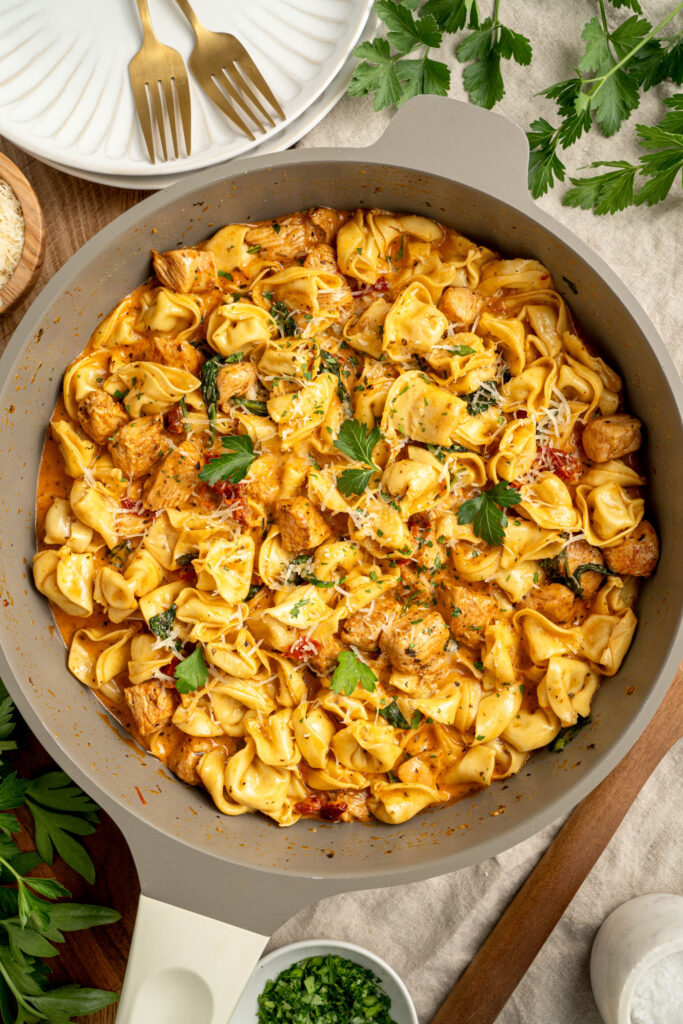 a large skillet with pasta in a creamy tomato sauce.