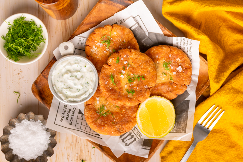 cooked seafood patties with lemon and dill sauce on the side.