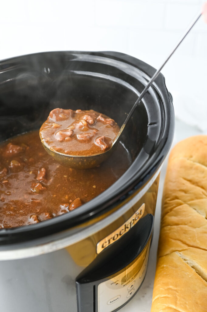 a ladle serving a hearty meat dish with gravy.