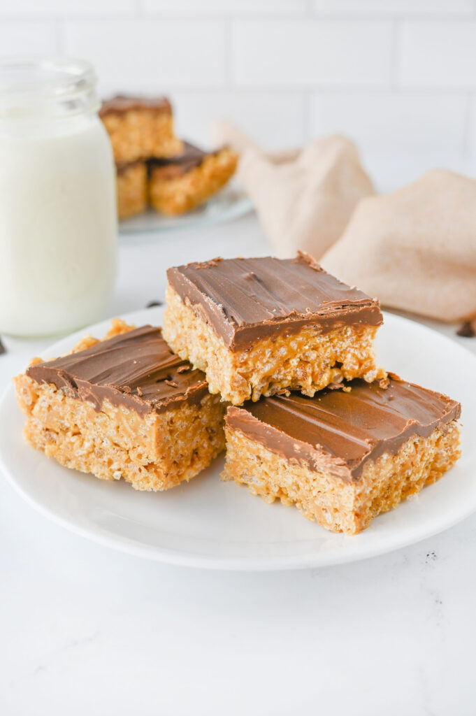 a no bake peanut butter cereal bar stacked on a white plate.