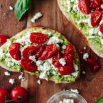 Avocado Toast with Tomato on a wood cutting board.