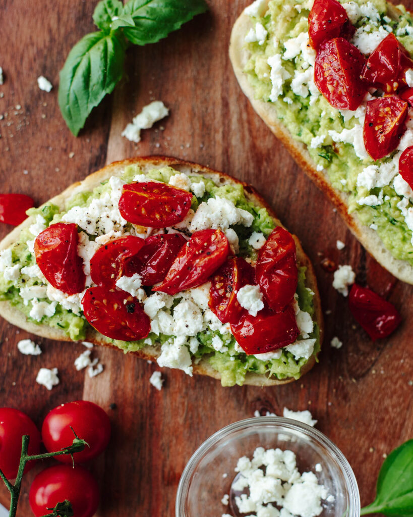 Avocado Toast with Tomato on a wood cutting board.