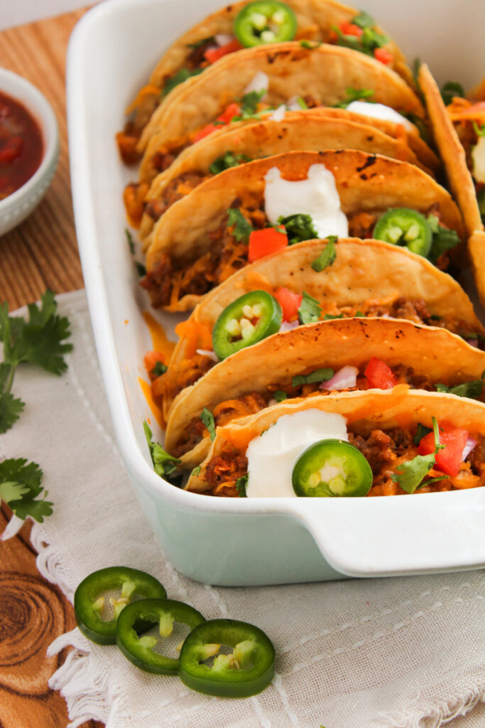 taco toppings on top of oven baked ground beef tacos.