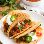 a serving of Mexican tortilla shells filled on a white plate.