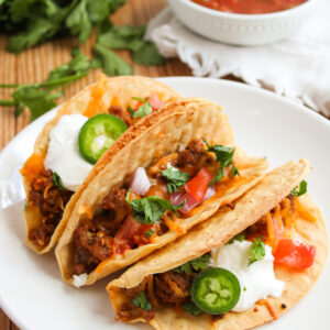 a serving of Mexican tortilla shells filled on a white plate.