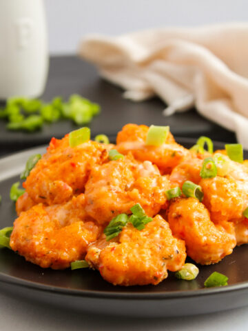 a black dinner plate with a spicy seafood mixture.