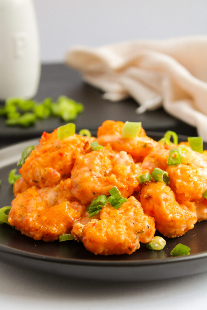 a black dinner plate with a spicy seafood mixture.